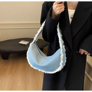 Detail of blue denim crescent bag featuring white faux fur trim and zip closure