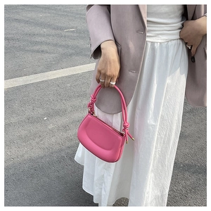 Detail of rose pink leather handbag with a unique knotted handle and gold zipper