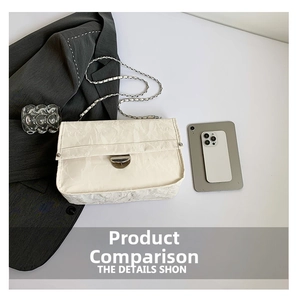 Detailed view of white pleated square bag with silver chain strap and metal clasp on desk