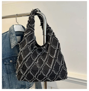 Detail of black denim tote bag with quilted diamond pattern and distressed frayed edges