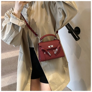 Close-up of wine red lychee pattern leather handbag with metal turn-lock and strap detail