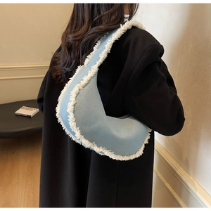 Detail of light blue denim underarm bag with white plush trim and fringe on a model