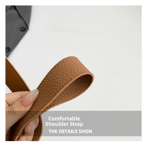 Detail of the wide brown lychee grain leather shoulder strap with precise stitching quality