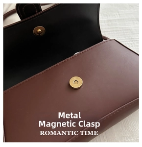 Detail shot of the golden magnetic snap closure on a brown leather shoulder bag