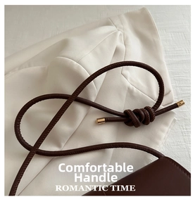 Close-up of dark brown leather handle with knotted design and gold metal accents