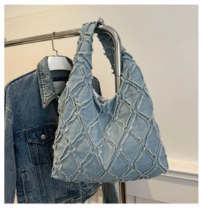 Detail of light blue denim tote with quilted diamond pattern and distressed frayed edges