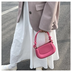 Detail of magenta structured handbag featuring a decorative knot handle and smooth leather