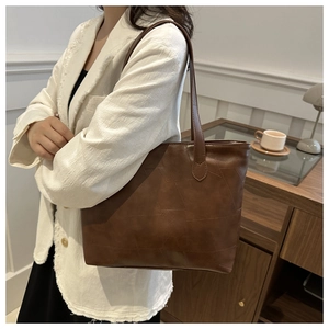 Detail of vintage brown tote bag with geometric stitching shown on shoulder