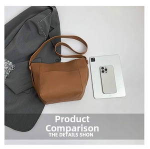 Brown lychee texture leather tote bag with wide strap next to tablet and grey blazer