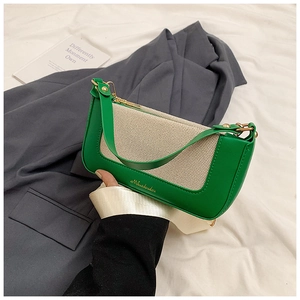 Dettaglio delle cuciture in pelle verde e tela beige sulla borsa a spalla baguette