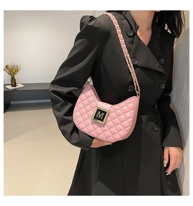 Detail of a bright pink quilted half-moon shoulder bag with a gold M buckle and chain