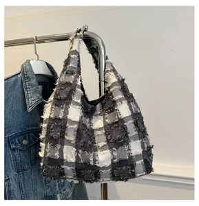 Detailed view of frayed edges on a black and white checkered tote bag with tweed texture