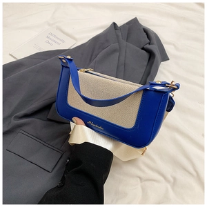 Dettaglio borsa a tracolla blu e beige con doppia tracolla e logo dorato del marchio