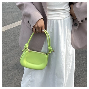 Detail of neon green crescent handbag with knotted handle and gold metal zipper