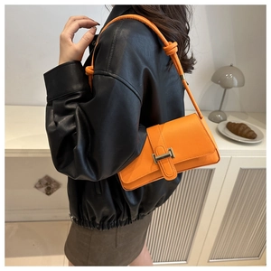Detail of trendy orange underarm bag with gold clasp and knotted strap shown in interior