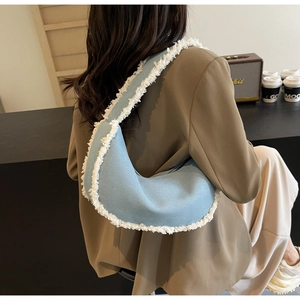 Detail of light blue denim half-moon shoulder bag with white fleece trim and fringe edge