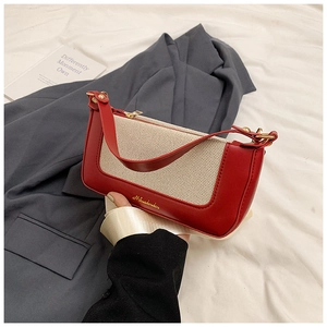 Dettaglio della pelle rossa e della trama intrecciata crema con logo dorato sulla borsa