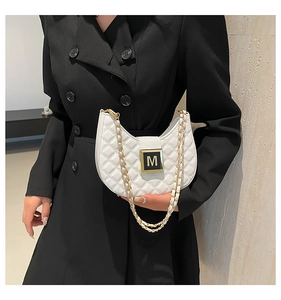 Close-up of quilted crescent shoulder bag in creamy white with metallic M logo buckle