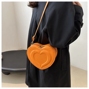 Dettaglio di una borsa a tracolla arancione a forma di cuore con scritta Fashion & Bags