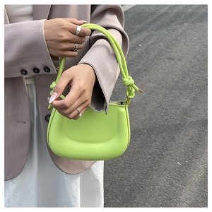 Detail of neon green leather handbag with unique knotted handle and secure zipper closure