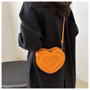 Dettaglio della borsa a tracolla arancione a forma di cuore con trama a rilievo e zip metallica