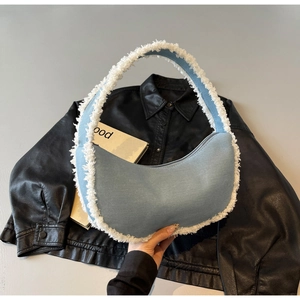 Detail of light blue denim crescent bag featuring trendy white frayed edges and silver zipper