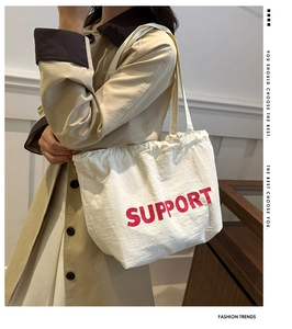 Close-up of white canvas tote bag with red SUPPORT print and durable shoulder strap