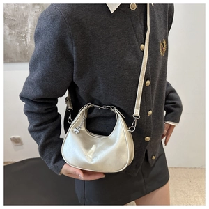Detail of silver crescent moon shoulder bag with metallic texture and cute bear charm