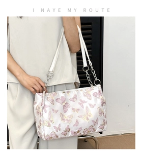Detail der weißen Satin-Tasche mit lila Schmetterlingsstickerei und Kettenriemen