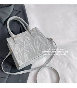 Close-up of the light gray wrinkled texture material and metallic hardware on the handbag