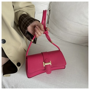 Detail of fuchsia leather crossbody bag featuring gold H-buckle and rope style strap