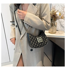 Close-up of black quilted crescent bag with gold M-logo buckle and chain strap detail