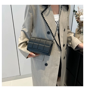 Close-up of black quilted leather crossbody bag with metallic chain strap on model