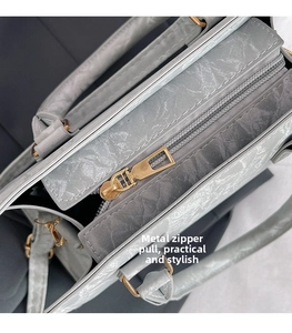 Detail of gold metal zipper and gray textured faux leather on a large tote bag
