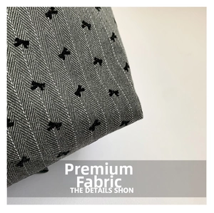Close-up of grey herringbone fabric with black bow tie embroidery details