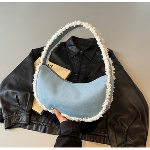 Close-up of crescent denim bag with white faux fur trim and frayed edge details