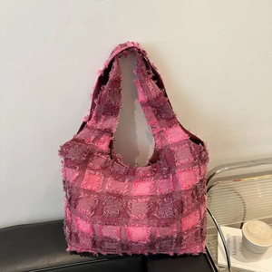 Pink and purple checkered tweed tote bag with fringe details in a modern city setting