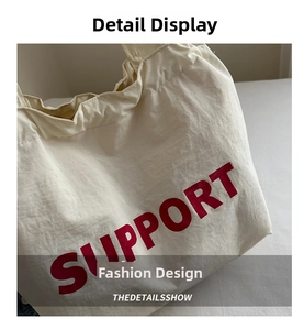 Detailed close-up of the fine canvas texture and red SUPPORT print on the cream tote bag