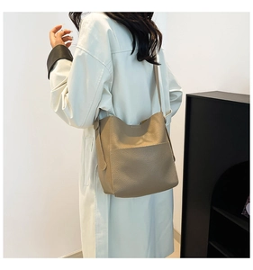 Taupe lychee grain leather bucket bag showing natural drape on model's shoulder
