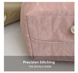 Detail shot of precise pink leather stitching and decorative white pearls on the bucket bag