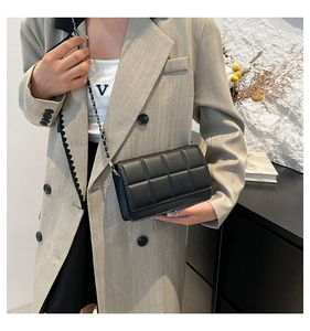 Detail view of a black quilted square crossbody bag with silver chain strap and flap closure