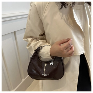 Detail of dark brown crescent bag with glossy finish and stylish silver chain handle