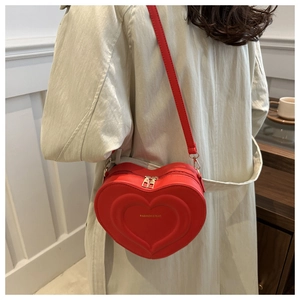 Dettaglio di una borsa a tracolla rossa a forma di cuore con design a doppio cuore goffrato