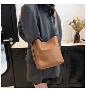 Detailed texture of brown pebble grain leather bucket bag on a model in home setting