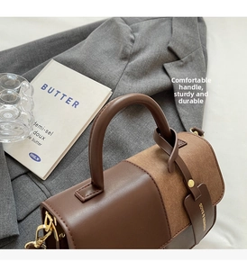 Detail of color-block handbag with round handle and metal hardware on a blazer