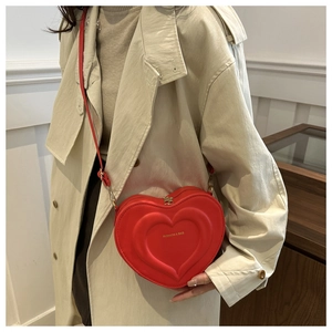 Dettaglio della borsa a tracolla rossa a forma di cuore con rilievo e cerniera dorata