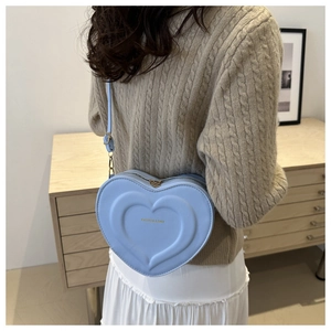 Dettaglio della borsa a tracolla azzurra a forma di cuore indossata da una modella