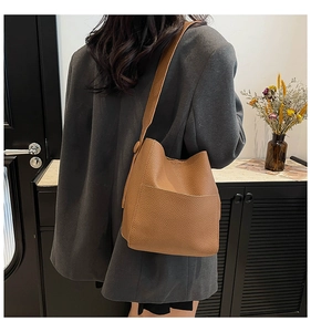 Detailed view of brown litchi grain leather bucket bag with wide shoulder strap