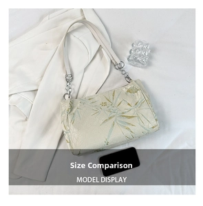 Close-up of bamboo leaf embroidery on cream shoulder bag with metal chain strap