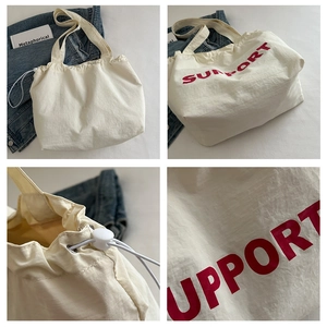 Detail of white canvas tote bag with red SUPPORT print and functional drawstring closure